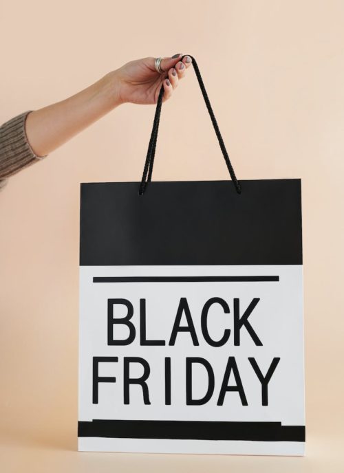 person holding black and white black friday paper bag