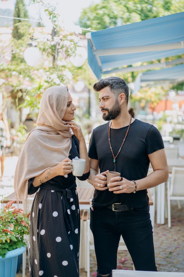 a couple standing while holding cups of coffee