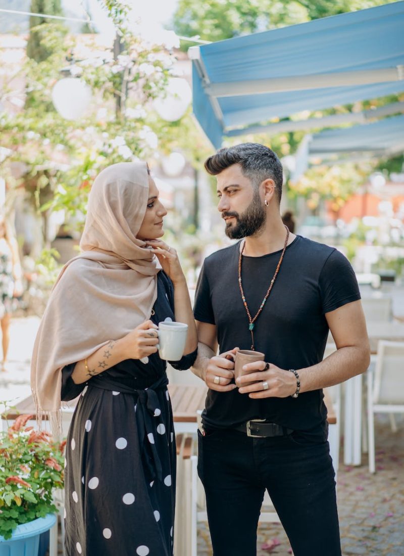 a couple standing while holding cups of coffee