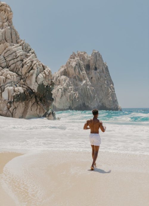shirtless man walking towards the sea
