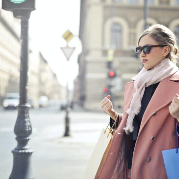 woman in pink coat holding shopping bags