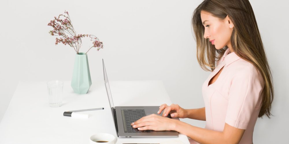 woman in pink dress using laptop computer