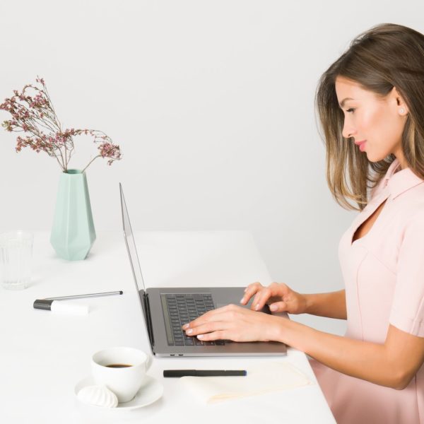 woman in pink dress using laptop computer