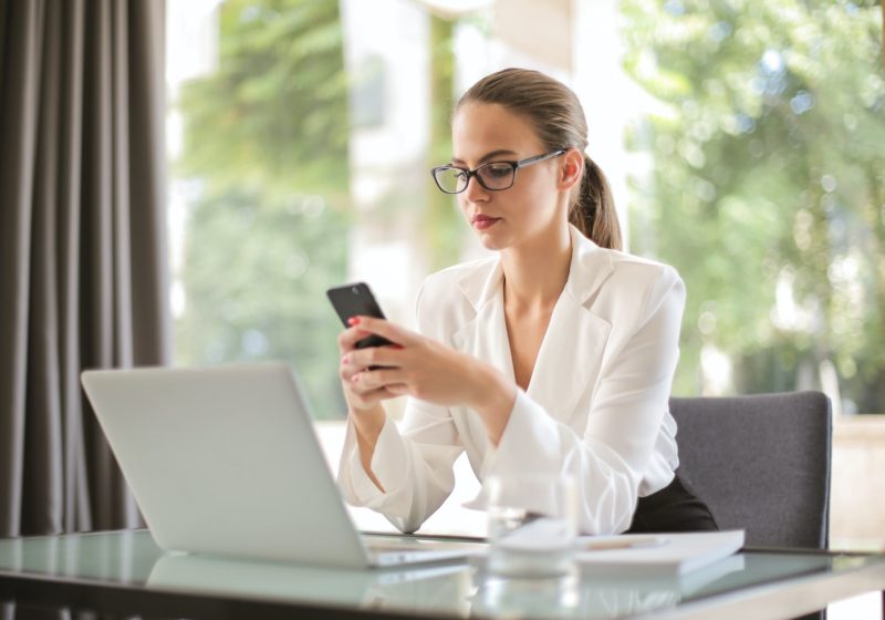serious businesswoman using smartphone in workplace