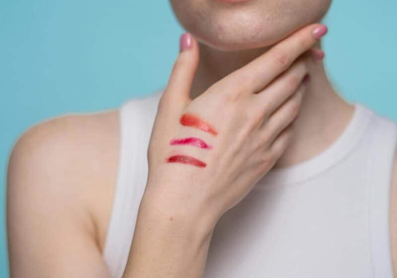crop photo of woman in white tank top with different shades of red lipstick on hand